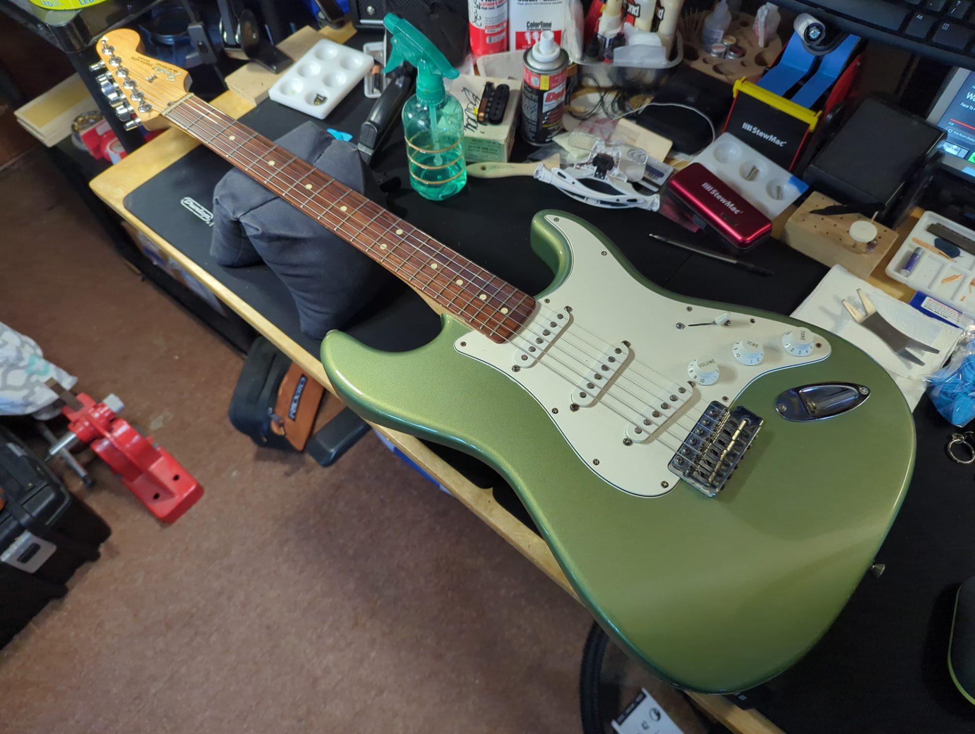 Green electric guitar on a technician’s repair bench